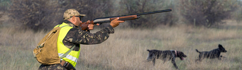 Hunter man in camouflage with a gun during the hunt in search of wild birds or game.