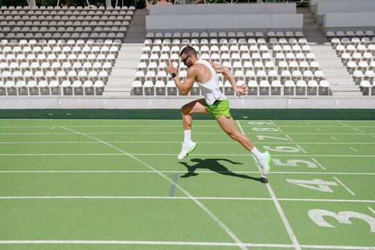 Man running on sports track on sunny day