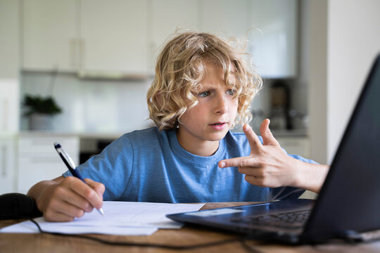 Boy counting through fingers looking at laptop