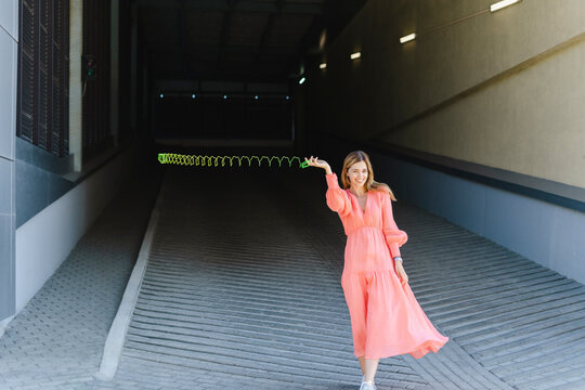 Playful woman spinning metal coil toy on footpath