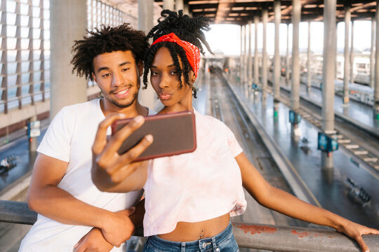 Multiracial friends taking selfie on mobile phone at railroad station