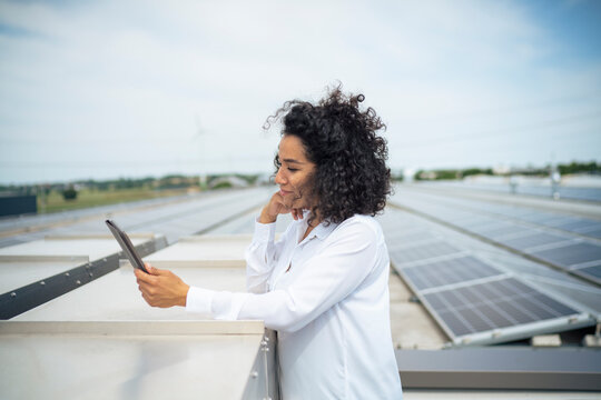 Businesswoman Looking At Tablet PC In Front Of Solar Panels On Rooftop