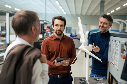 Business colleagues discussing over wind turbine model in industry