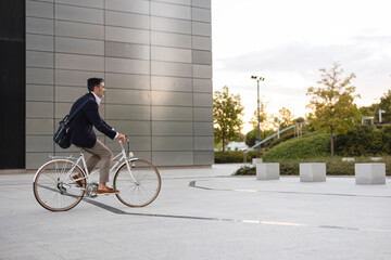 Businessman riding bicycle in front of office building