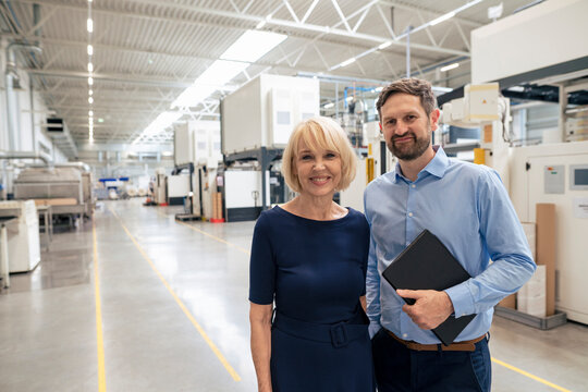 Happy senior businesswoman with colleague standing in industry