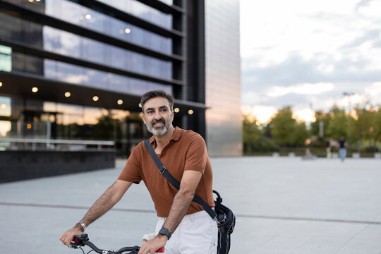 Thoughtful businessman with bicycle in front of office building
