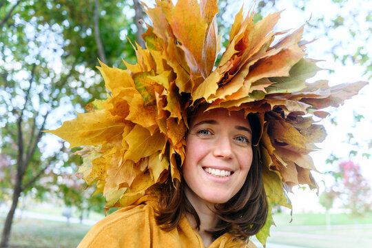 Smiling woman wearing wreath made of autumn leaves in park