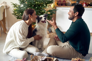 Multi ethnicity couple spending time with dog at Christmas