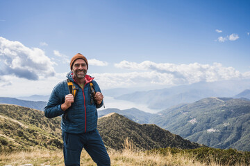 Mature man with knit hat standing in front of mountains