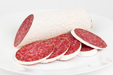 Salami slices on a white plate close-up, pork sausage.