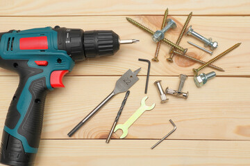 set of tools on wooden table, a electric screwdriver with a set of drill bits and screws with bolts. work tool on wooden background. Hand tool closeup