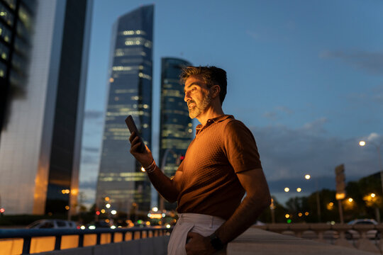 Mature Businessman Using Mobile Phone In City At Night