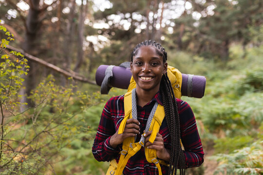 Happy young woman with backpack standing in forest