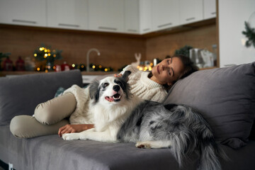 Fototapeta na wymiar Woman with dog chilling at the sofa during the Christmas