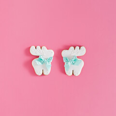 Minimal holiday composition made of two gingerbread reindeers against pink background. Warm Christmas aesthetic. New Year flat lay scene with copy space.