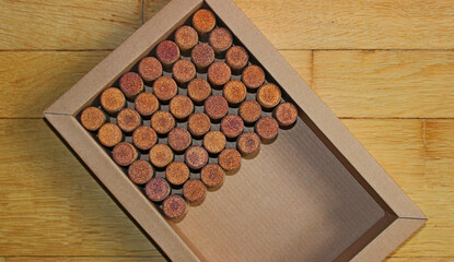 A box filled halfway with wine corks at an angle on wooden planks surface top view
