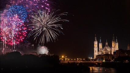 Fototapeta premium Photograph of the fireworks at the end of the Fiestas del Pilar 2022 in Zaragoza, with the Basilica del Pilar in the background and the Ebro River, Spain. 
