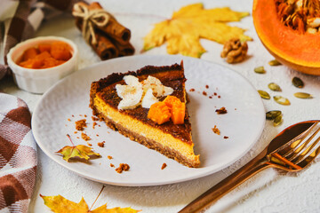 Homemade pumpkin cheesecake decorated with whipped cream on gray plate.