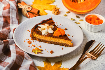 Homemade pumpkin cheesecake decorated with whipped cream on gray plate.