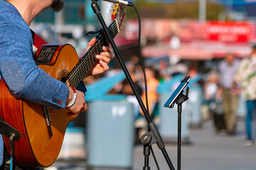Street performer man playing guitar in the square in focus