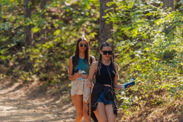 Sisters hiking through beautiful woods while wearing a backpack and enjoying nature. Female bonding.