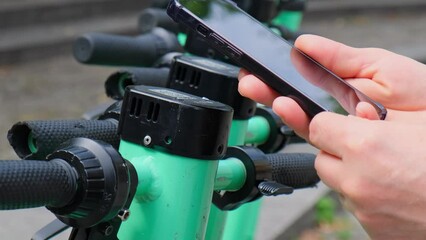 Woman using app on smartphone to unlock electric scooter on the street. Woman scanning qr code on e-scooter, rental service app. Alternative transportation in city. Eco friendly transportation modern