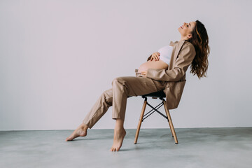 Attractive young pregnant woman sitting on a chair isolated over white background