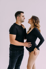 Young man standing with his pregnant woman isolated over white background wall. Looking aside.