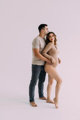 Young man standing with his pregnant woman isolated over white background wall. Looking aside.