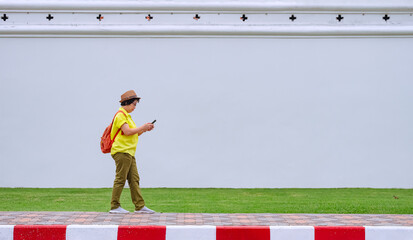 Adult female tourist using smartphone to searching tourist information while walking on sidewalk in...