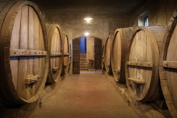 Ancient underground wine cellar with wooden oak casks for wine aging