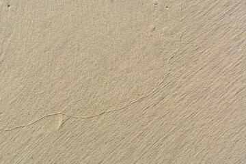 Drawing on the sand from the waves. Traces of the surf. Background for a vacation layout.