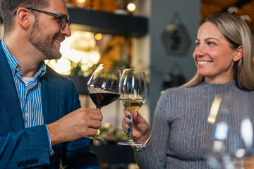 young, lovely couple making a toast for many more beautiful moments, with quality and rich white wine in the restaurant