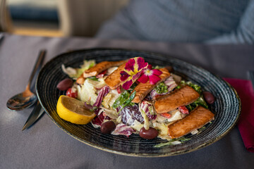 A close-up shot of a dish served at a restaurant for dinner. in the frame are hands and an escajg.