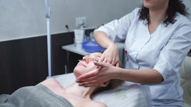 Attractive female at spa health club getting a facial massage. Beautician doing massage of face, neck and shoulders ofbeautiful young woman at luxury beauty salon