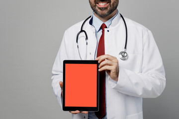 Male doctor man wears white medical gown suit stethoscope work in hospital tablet pc computer blank screen workspace area isolated on plain grey color background studio. Healthcare medicine concept.