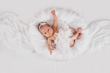 sweet newborn baby in dress with feathers