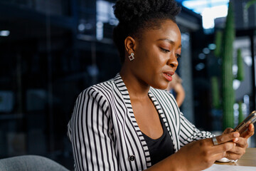 Happy woman video calling on smartphone in office