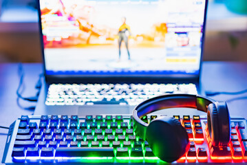 Pro gaming illuminated desk, headset, keyboard, computer neon lights. Cyber sport equipment laying on desktop, ready for online video gaming.Dark shot. © ARVD73