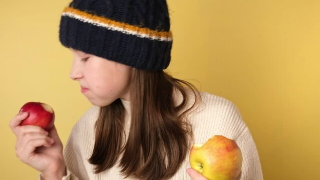 Teen Girl Eating an Apple Isolated on Yellow. Cute Young Girl in Knitted Cozy Clothes Biting Apples on Color Studio Background. Healthy Food Harvest. Autumnal Mood. Fall Season, Sale. Autumn Leaves.