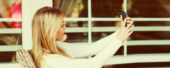 Young woman taking selfie with smartphone sitting at the table in a cafe