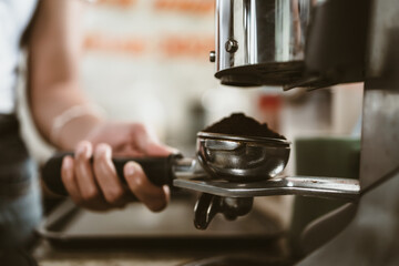 barista use bottomless filter with grinder machine at coffee shop. coffee maker concept.