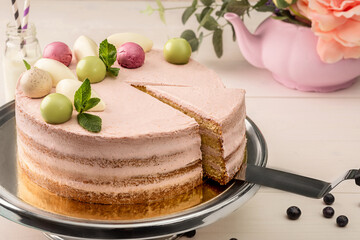 Sponge cake with berry cream garnished with balls of glazed chocolate, mousse and fresh mint