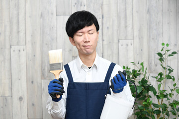 刷毛を持ちながら困るエプロン姿の若い男性