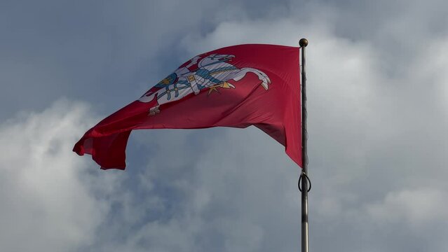Flag with coat of arms of Lithuania flying with sky at background