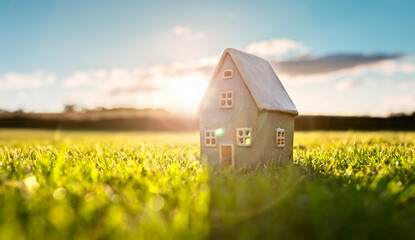 Model detatched cottage house in empty field at sunset background concept for construction and real...