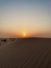 Fototapeta na wymiar Sunset in the desert. Sun goes down above a dune.