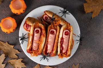 Themed food for Halloween party - hot dog with bloody sausage fingers in ketchup buns and carrot on...