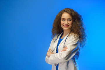 Studio shot of a young female doctor looking at camera against a blue background.