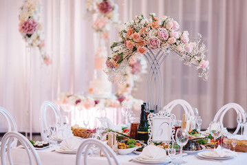 Wedding luxury decor and pink flowers. Wedding reception table setting on wedding day. A composition of flowers and greenery is on a festive table at the wedding banquet hall. Close up.